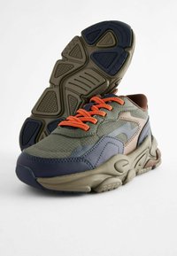 Synthetischer Sneaker in dunkelgrün, marineblau und beige. Texturiertes Obermaterial, markante Gummisohle und orangefarbene Schnürsenkel. Verfügt über ein geschichtetes Design.