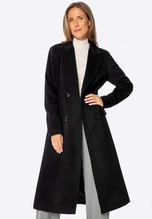 Abrigo negro de doble botonadura hecho de tela suave, con solapas anchas, bolsillos y un corte largo y recto. Diseño minimalista.