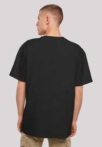 Schwarzes Baumwoll-T-Shirt mit lässigem Schnitt, Rundhalsausschnitt und kurzen Ärmeln, von hinten auf einem neutralen Hintergrund gezeigt.