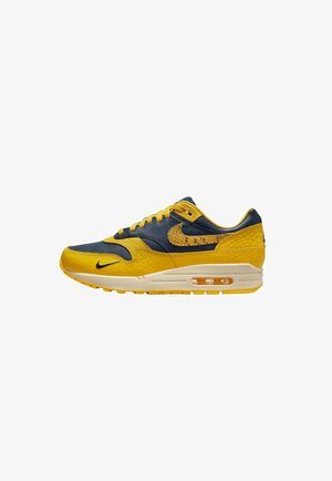 Sneaker Nike Air Max con una combinazione di colori giallo e blu navy, materiali in pelle e testurizzati, collare imbottito e unità d'aria visibile nella suola.
