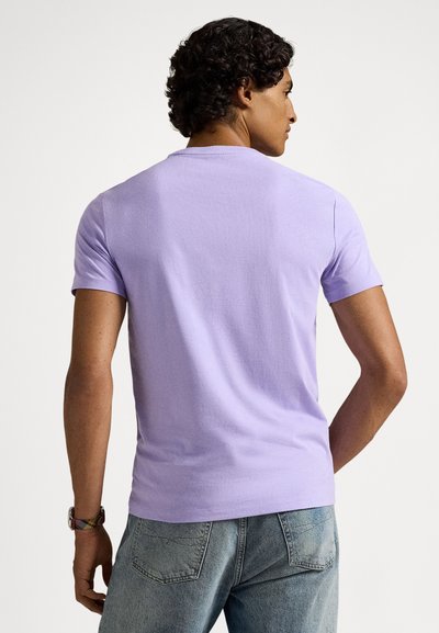 Levanduľovo biele tričko s okrúhlym výstrihom a krátkymi rukávmi, zobrazené zozadu. Neformálny strih s minimálnymi dizajnovými detailmi.