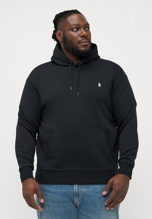 Zwarte hoodie van katoen, met een voorzak en een klein geborduurd logo op de borst. Gekocht met lichtblauwe jeans.