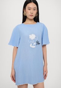 Blaues Leinenkleid mit kurzen, gewellten Ärmeln, das mit weißen Blumenstickereien und Text verziert ist. Glatte Textur, entspannte Passform, knielanges Design.