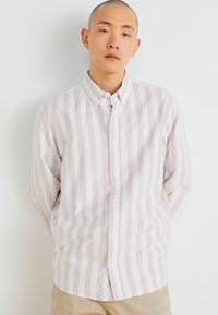 Camisa de manga larga con botones, que presenta rayas verticales en rosa y blanco. Está hecha de una tela suave, con cuello y puños ajustables.