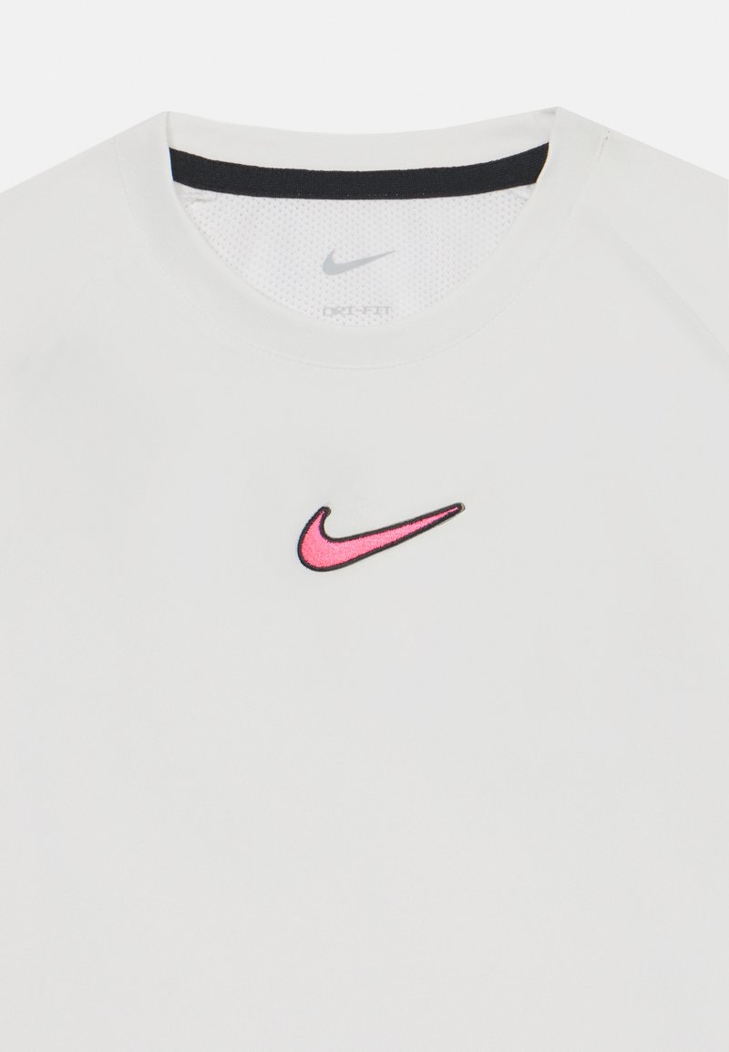 Biała koszulka Nike Dry-Fit z różowym i czarnym haftowanym logo. Kołnierz ma czarny akcent oraz teksturowaną wewnętrzną warstwę.