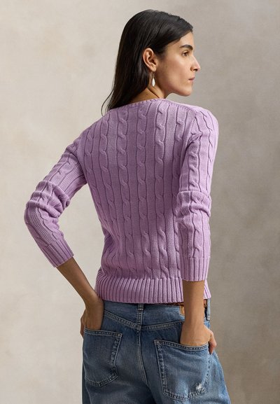 Μπλούζα από πλεκτό νήμα σε λιλά χρώμα με μανίκια τριών τετάρτων και ριμπέν τελείωμα, συνδυασμένη με μπλε τζιν παντελόνι. Η πίσω όψη αποκαλύπτει την υφή και τις λεπτομέρειες των ραφών.