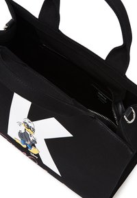 Sac fourre-tout noir en toile avec un logo blanc et un graphique de dessin animé. Dispose de deux poignées supérieures et d'une poche zippée à l'intérieur.
