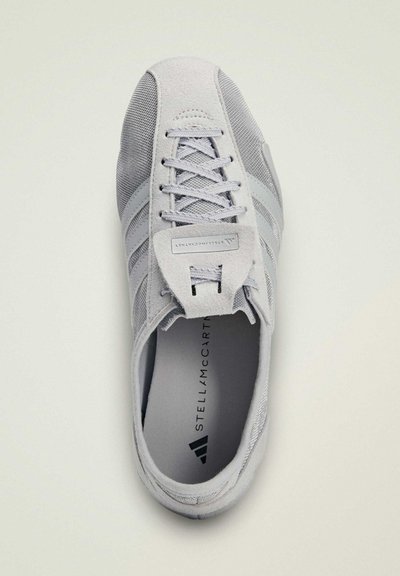 Baskets gris clair en suède et mesh, à lacets sur le devant, avec trois bandes latérales et le logo "Stella McCartney" à l'intérieur de la chaussure.