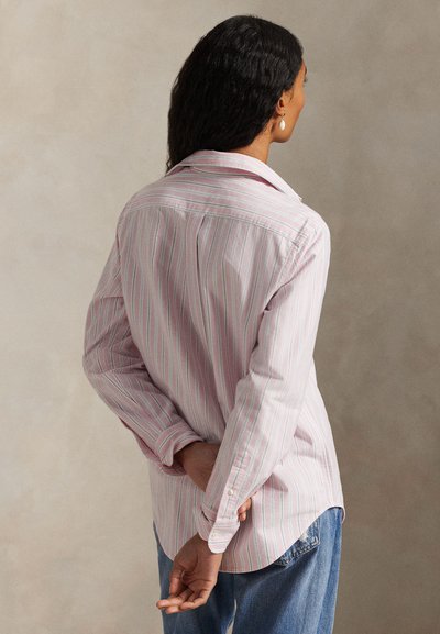 Ροζ ανοιχτό και λευκό ριγέ πουκάμισο με μακριά μανίκια, γιακά, μανσέτες με κουμπιά και άνετη εφαρμογή, συνδυασμένο με μπλε τζιν παντελόνι.