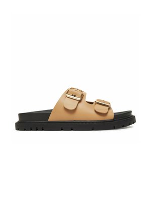 Tan farvet sandal med sort sål og to justerbare remme med spænder over toppen.
