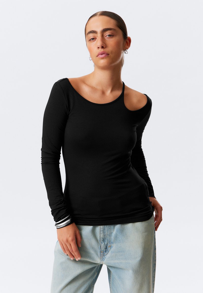 Schwarzes Langarmshirt mit asymmetrischem Ausschnitt und einem Schulterausschnitt. Weiches, elastisches Material mit figurnaher Passform und subtiler Textur.