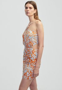 Multikleurige aansluitende jurk met asymmetrische snit, voorzien van abstracte patronen in oranje en blauw, geknoopte banddetails en textuur met geplooid stof.