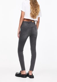 Harmaat kapeat farkut, denim-materiaalia; keskikorkea vyötärö, etu- ja takataskut, yhdistetty mustien slip-on-kenkien kanssa.