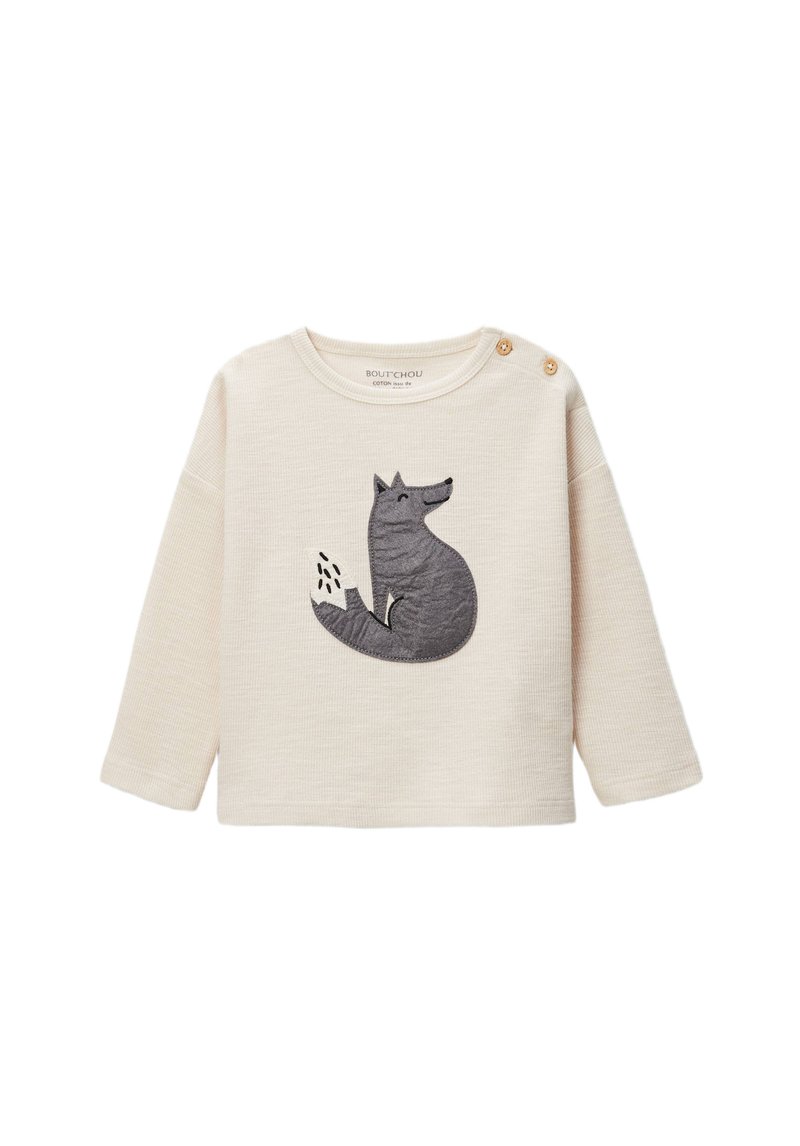 Chemise crème à manches longues avec une broderie texturée de loup gris sur le devant. Comprend deux boutons en bois décoratifs sur l'épaule.