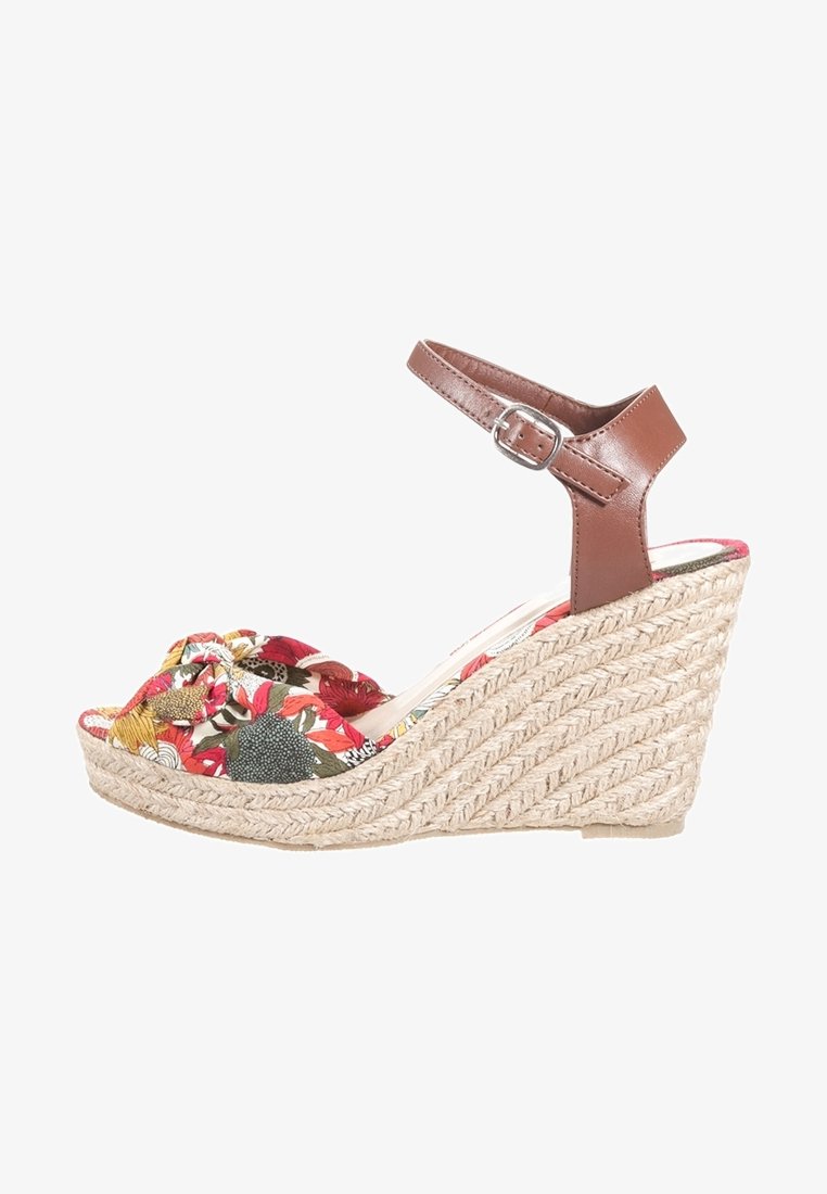 Sandale compensée avec une semelle en jute tressé, présentant une tige en tissu floral rouge et vert, et une bride de cheville en cuir marron avec boucle.