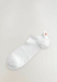 Vit ankelsocka med en mjuk textur, med en orange broderad design nära kanten. Enkel design utan mönster.