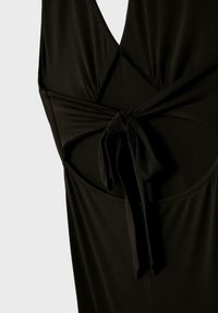 Robe noire sans manches avec un décolleté en V profond et un nœud à l'avant noué au-dessus d'une découpe sur le torse.