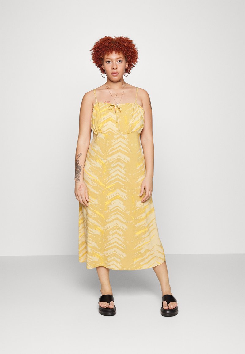 Vestido midi amarelo, de corte solto, com um design padronizado. Apresenta alças ajustáveis, um corpete pregueado e um detalhe de laço na parte da frente.