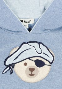 Felpa leggera blu con cappuccio, caratterizzata da un ricamo di un orso con cappello da pirata, benda sull'occhio e bandana. Tessuto morbido simile al pile con cuciture dettagliate.