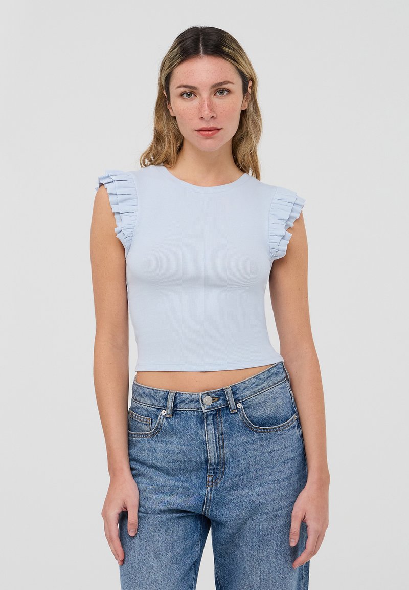 Top corto a righe blu chiaro con maniche corte a volant, abbinato a jeans in denim blu a vita alta. Scollo rotondo semplice, design minimale.