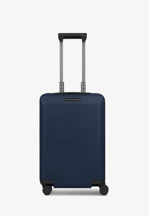 Maleta rígida azul marino con acabado texturizado, asa retráctil y cuatro ruedas giratorias para facilitar la movilidad. Marca en el frente.