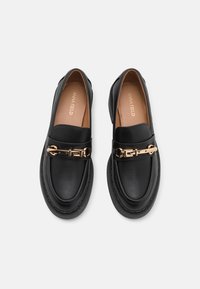 Schwarze Lederloafers mit einer goldfarbenen Schnallenakzent. Abgerundete Zehenpartie, gepolsterte Innensohle und genähte Verzierungen rund um die Sohle.