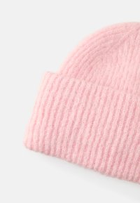 Gorro de malha rosa com textura canelada. O tecido parece suave e quente, com um ajuste confortável para cobrir a cabeça.