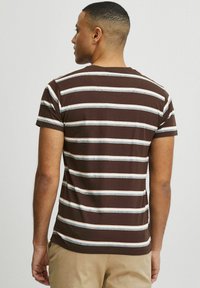 Brun randig t-shirt med kort Ärmar, med vita och ljus persikofärgade horisontella ränder. Mjuk bomullsmaterial med rund halsringning.