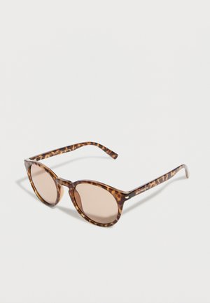 Okulary przeciwsłoneczne w kolorze żółwia z zaokrąglonymi soczewkami i jasnobrązowym odcieniem, wyposażone w cienkie zauszniki oraz subtelny napis z nazwą marki z boku.