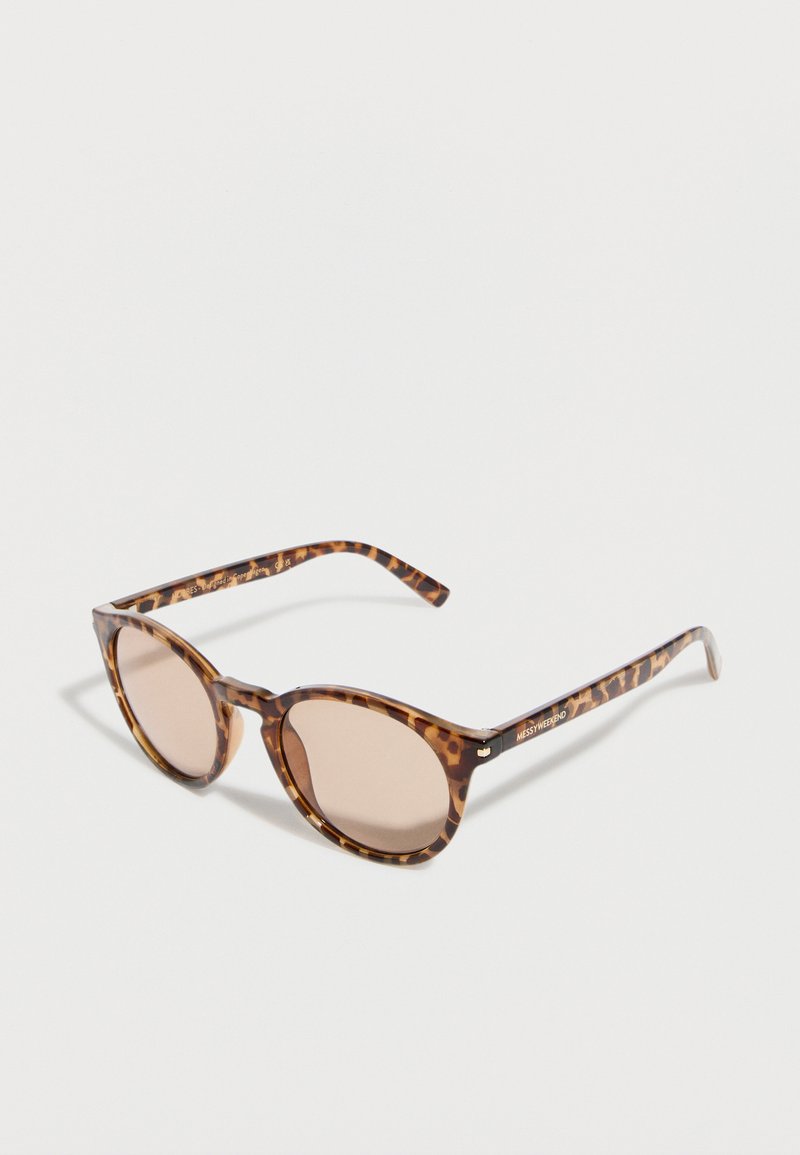 Γυαλιά ηλίου με φαρδιά σκελετά σε σχέδιο χελώνας, στρογγυλούς φακούς με ανοιχτό καφέ απόχρωση, λεπτά πλαϊνά μπράτσα και διακριτικό λογότυπο στην πλευρά.