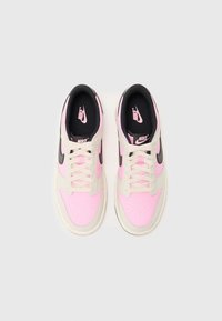 Nike αθλητικά παπούτσια με ροζ συνθετικό πάνω μέρος, μαύρες λεπτομέρειες, μπεζ κορδόνια και διάτρητο σχέδιο για αερισμό. Λευκή καουτσούκ σόλα.