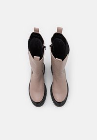 Light pink leather knee-high boots with black accents, textured lining, flat rubber sole, and back pull tab, featuring a side zipper.