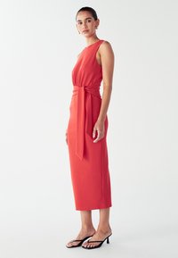 Asymmetrisches rotes Midi-Kleid mit gebundenem Taillengürtel, aus glattem Stoff, mit ärmellosem Design und geradem Saum.