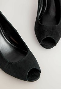 Mustad sametist peep-toe kingad, millel on sile viimistlus ja madal konts. Esiküljel lai ava ja ümarad tallaservad.