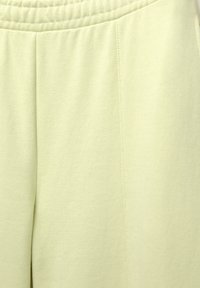 Helle grüne Baumwoll-Sweatpants mit elastischem Bund, ausgestattet mit einer glatten Textur und Seitennähten, die für Komfort und einfache Trageweise konzipiert sind.