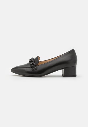 Ballerines noires en cuir à talons bas avec un bout pointu et un détail de nœud décoratif à l'avant. Texture lisse et design minimaliste.