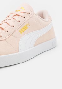 Svijetloružičaste tenisice od suedea s bijelim gumenim potplatom i bočnom prugom, s zlatnim Puma logotipom i vezicama, naglašavajući elegantan, klasičan dizajn.