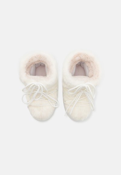 Hvite faux fur tøfler med en myk rosa fôr, med hvite snørebånd og rund tå. Designet inkluderer en plysj, polstret krage.