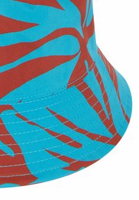 Cappello a secchiello rosso e azzurro chiaro con grandi motivi a foglia, tessuto morbido, visiera curva e cuciture a vista lungo il bordo.