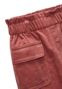 Pantalon en velours côtelé de couleur rose poussiéreux avec une surface texturée, une taille élastique et des poches latérales pour plus de fonctionnalité.