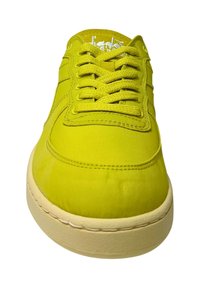 Sneaker verde lime con una texture liscia, punta arrotondata e suola piatta. Presenta un design con lacci e cuciture tono su tono, insieme a una soletta di colore crema.