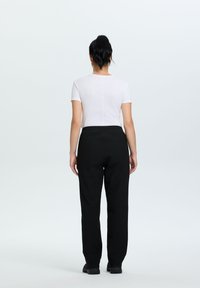 Zwarte elastische taillebroek met een relaxed fit. Gecombineerd met een getailleerde witte T-shirt met korte mouwen. Eenvoudige, gladde stof zonder patronen.