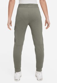 Olivgrön sweatpant med ribbad midjeband, smalnande ben och cargo-fickor, i ett mjukt tyg med slät yta.