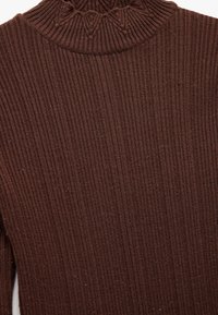Pull en maille côtelée marron avec un col montant, présentant un motif texturé au niveau du col, fabriqué en matière douce.