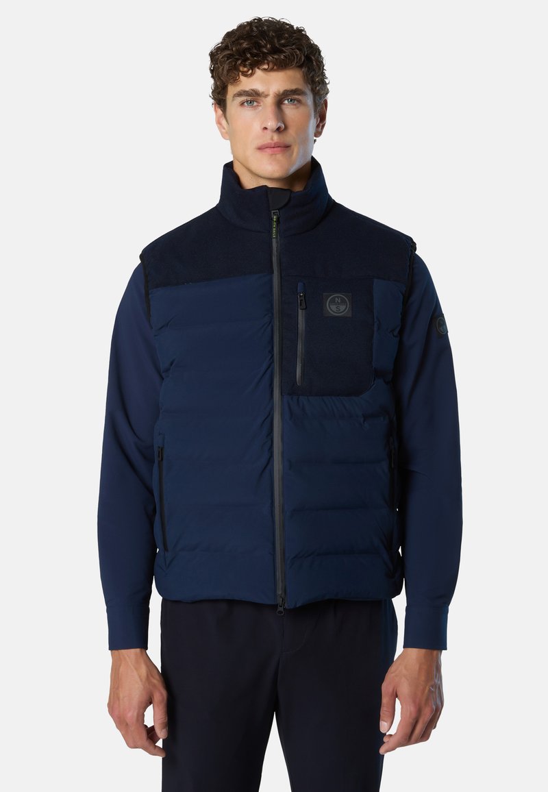 Dunkelblaue Steppweste mit Reißverschluss vorne, hohem Kragen und Fleece-Akzenten. Mit Brusttasche und seitlichen Reißverschlusstaschen. Strukturierter Stoff.
