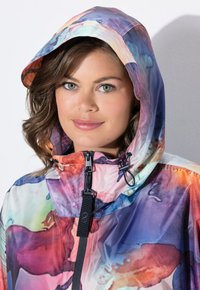 Farverig vandtæt jakke med en gradient i pink, blå og lilla nuancer, med en struktureret hætte og justerbar hagestraps.