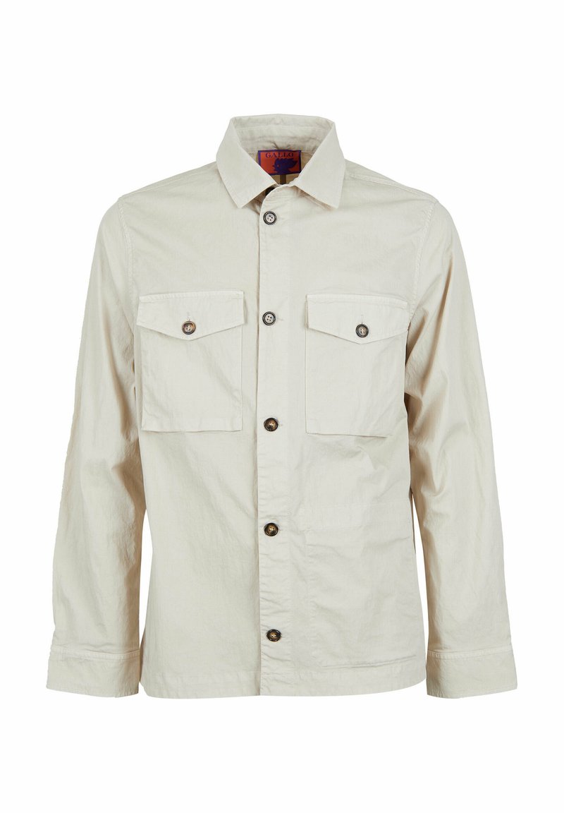 Camicia beige a bottone realizzata in tessuto leggero, con due tasche frontali, bottoni marroni e colletto a punta.