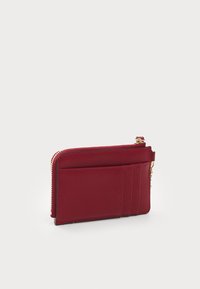 Portafoglio rosso in pelle con chiusura a zip, dotato di tre scomparti per carte su un lato e con una finitura liscia. Forma rettangolare compatta.