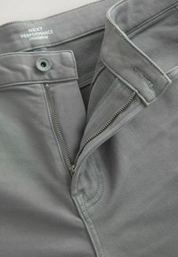 Graue gerade geschnittene Hosen mit sichtbarem Reißverschluss, Knopfverschluss und weichem Stofftextur. Sie verfügen über einen Bund mit subtilen Stickdetails.