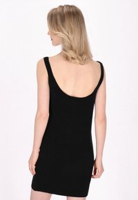 Schwarzes, ärmelloses Kleid mit einem runden Rückendesign. Hergestellt aus weichem Stoff, weist es eine figurbetonte Silhouette und einen minimalistischsten Stil auf.